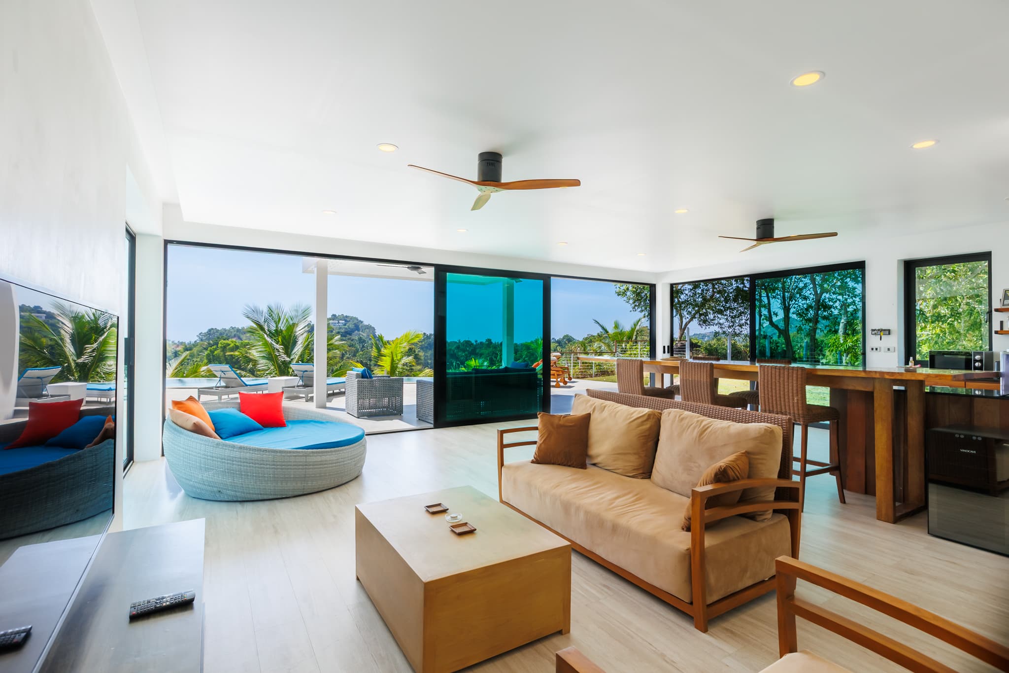 Wohnzimmer mit Sofa, rundem Daybed und Poolblick