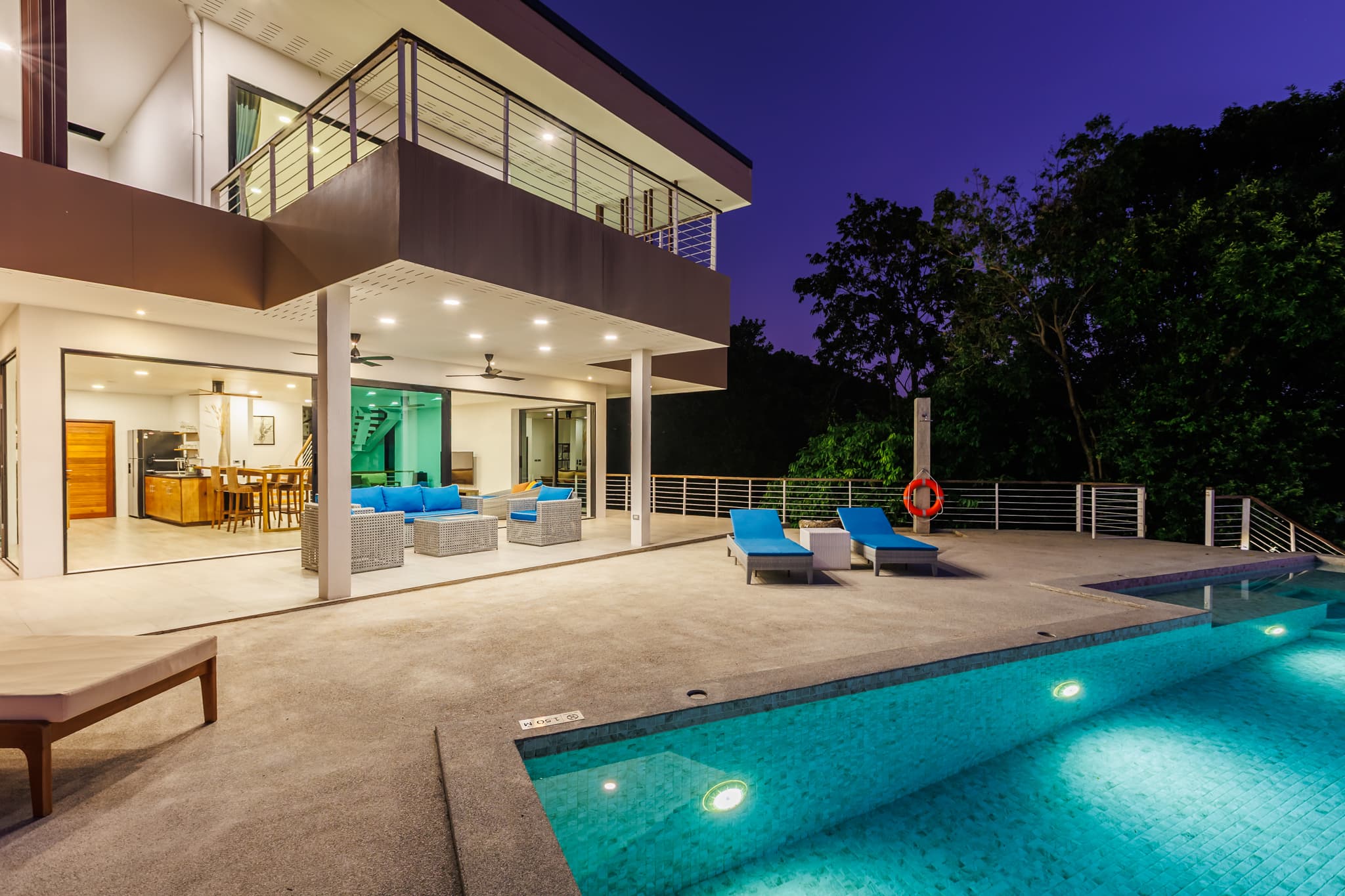 Beleuchtete Poolterrasse und Villa in der Abenddämmerung